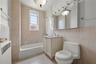 Bathroom featuring tile walls, shower / washtub combination, vanity, and radiator
