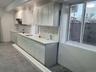 Kitchen with tasteful backsplash, under cabinet range hood, and white cabinets