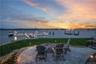 View of dock with a water view, a patio, a lawn, and a fire pit