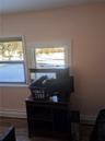 Home office with dark wood-type flooring and a baseboard radiator