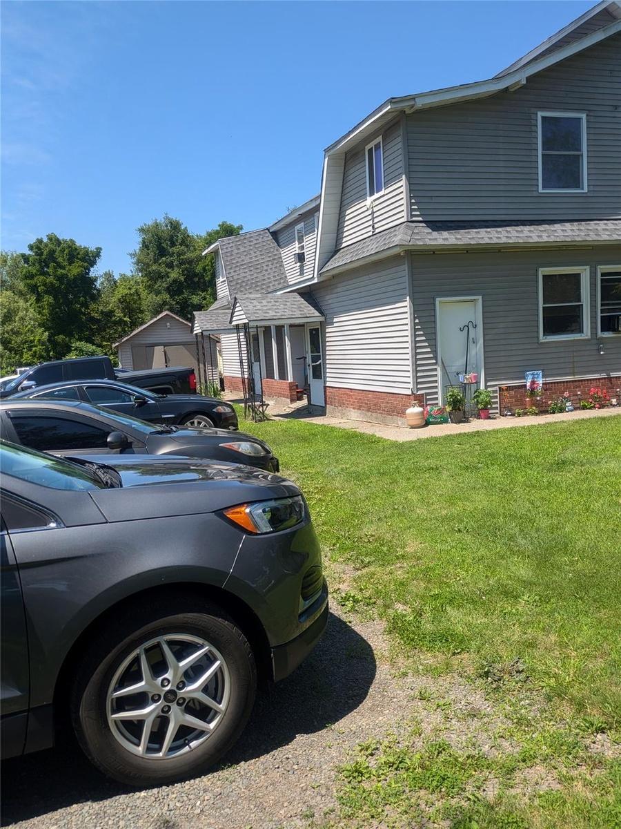 View of home's exterior featuring a shingled roof and a lawn