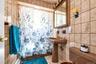 Bathroom with tile walls, tile patterned flooring, baseboard heating, and shower / tub combo