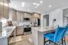 Kitchen with light stone counters, a breakfast bar, appliances with stainless steel finishes, decorative backsplash, and wine cooler