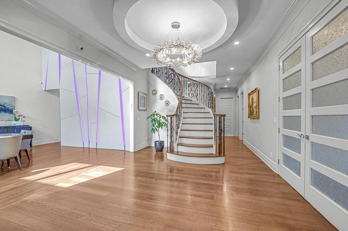 Entrance foyer featuring wood finished floors, a chandelier, stairs, recessed lighting, and a tray ceiling