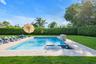 View of pool featuring a lawn, a pool with connected hot tub, and a patio