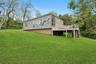 Back of property featuring stairway, a wooden deck, and a yard