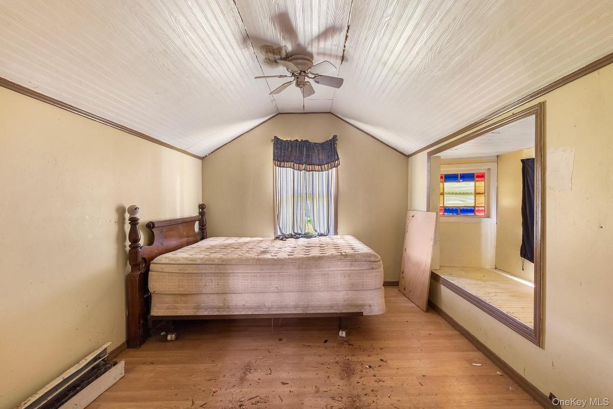 Bedroom with light wood finished floors, vaulted ceiling, ceiling fan, and ornamental molding