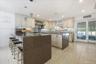Kitchen featuring a peninsula, dark stone countertops, pendant lighting, wall chimney exhaust hood, and cream cabinets
