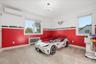 Bedroom featuring radiator heating unit, light carpet, multiple windows, and a wall mounted AC