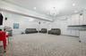 Living area featuring a chandelier, ornamental molding, a decorative wall, wainscoting, and light colored carpet