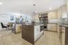 Kitchen with cream cabinetry, decorative backsplash, dark stone counters, a center island with sink, and recessed lighting