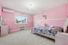 Carpeted bedroom featuring radiator heating unit, an AC wall unit, and a chandelier