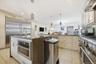 Kitchen with dark stone countertops, premium appliances, hanging light fixtures, range hood, and recessed lighting