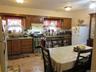 Kitchen featuring appliances with stainless steel finishes, a textured ceiling, under cabinet range hood, tasteful backsplash, and brown cabinetry
