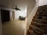 Basement featuring stairway, a ceiling fan, a baseboard radiator, and wood finished floors