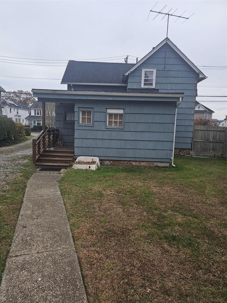 Rear view of property with a yard, a porch, and roof with shingles