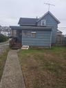 Rear view of property with a yard, a porch, and roof with shingles