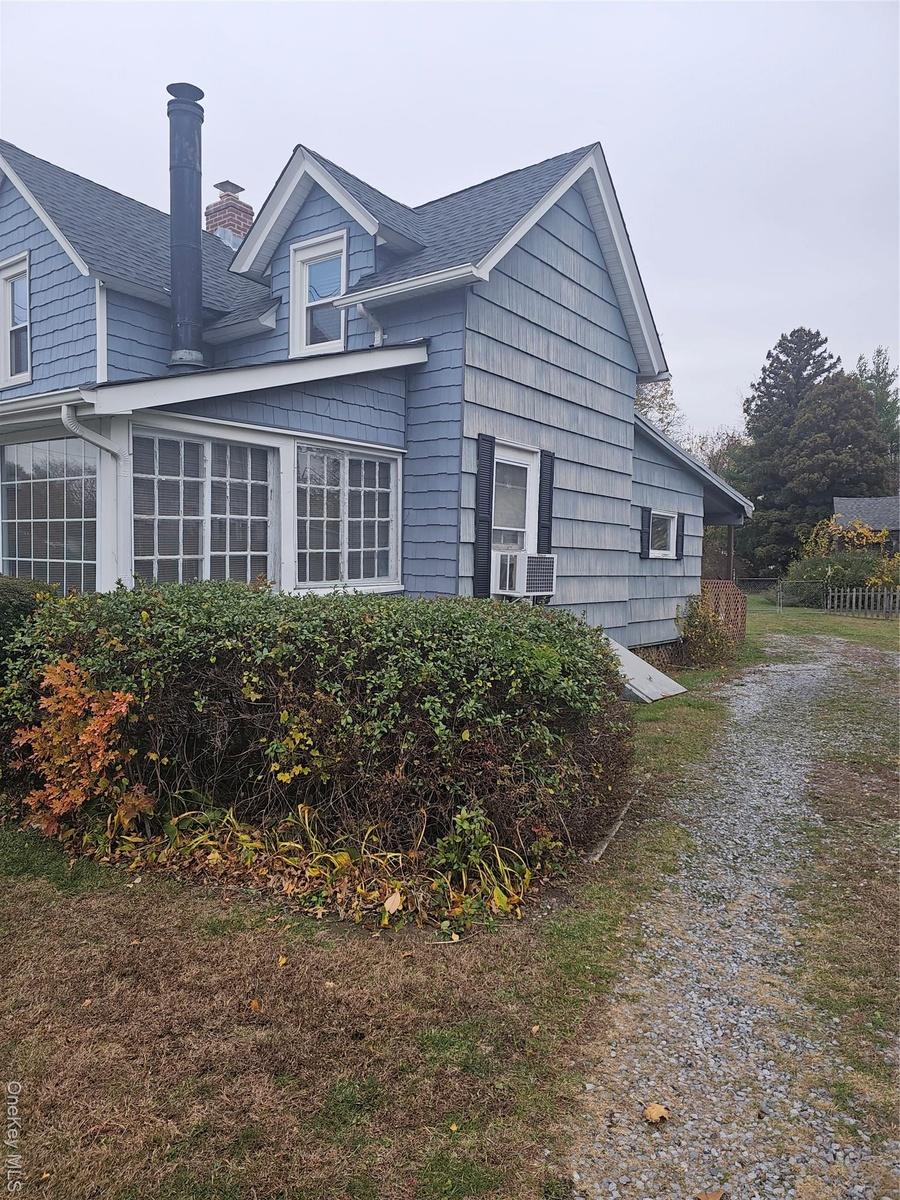 View of side of home featuring a chimney and a shingled roof