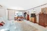 Carpeted living room with a desk and baseboards