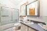 Bathroom with decorative backsplash, vanity, enclosed tub / shower combo, and vaulted ceiling
