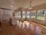Kitchen featuring an island with sink, white cabinetry, hanging light fixtures, light wood finished floors, and a chandelier