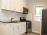 Kitchen with appliances with stainless steel finishes, tasteful backsplash, white cabinets, and light wood finished floors