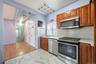 Kitchen featuring appliances with stainless steel finishes, light marble finish floors, backsplash, brown cabinetry, and light stone countertops