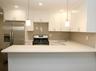 Kitchen featuring backsplash, white cabinets, appliances with stainless steel finishes, recessed lighting, and light stone counters