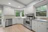Kitchen featuring appliances with stainless steel finishes, white cabinetry, stainless steel countertops, open shelves, and light wood-style floors