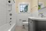 Full bathroom with tile walls, radiator heating unit, vanity, washtub / shower combination, and tile patterned flooring