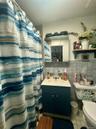 Full bath with tile walls, tile patterned flooring, curtained shower, and vanity