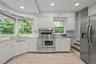 Kitchen with stainless steel appliances, stainless steel countertops, white cabinets, light wood-type flooring, and recessed lighting