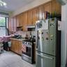 Kitchen with appliances with stainless steel finishes, brown cabinetry, light tile patterned floors, light countertops, and decorative backsplash