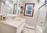 Full bathroom featuring vanity, a baseboard radiator, light tile patterned floors, and combined bath / shower with glass door