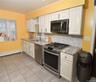 Kitchen featuring appliances with stainless steel finishes, backsplash, light stone countertops, light tile patterned floors, and ornamental molding
