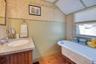 Full bath featuring a freestanding tub, vanity, wood finished floors, lofted ceiling, and wallpapered walls