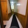 Corridor with light tile patterned flooring, wainscoting, radiator heating unit, and wood walls