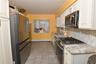 Kitchen featuring stainless steel appliances, light tile patterned flooring, decorative backsplash, light stone countertops, and white cabinetry