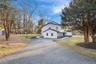 View of side of home with a lawn, asphalt driveway, and stone siding