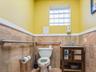 Half bath featuring a wainscoted wall, vanity, and tile walls