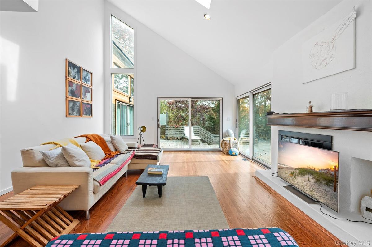 Living room with high vaulted ceiling, wood finished floors, recessed lighting, and a skylight