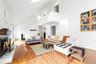 Bedroom with a warm lit fireplace, a towering ceiling, light wood-type flooring, and recessed lighting