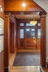 Foyer with light wood finished floors, crown molding, and decorative columns