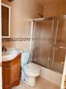 Full bathroom with tile walls, vanity, light tile patterned floors, and bath / shower combo with glass door