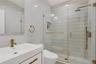Full bath featuring vanity, a stall shower, and tile walls