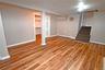 Finished basement with a baseboard radiator, light wood finished floors, and stairs