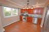 Kitchen with a baseboard radiator, appliances with stainless steel finishes, decorative light fixtures, dark wood-style flooring, and decorative backs