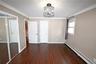 Unfurnished bedroom featuring a baseboard heating unit, dark wood-style floors, ornamental molding, a closet, and a chandelier