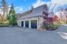3 Car Garage View of side of home with a gambrel roof, stone siding, an attached garage, and driveway