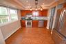 Kitchen with appliances with stainless steel finishes, a baseboard radiator, tasteful backsplash, hanging light fixtures, and dark wood finished floor